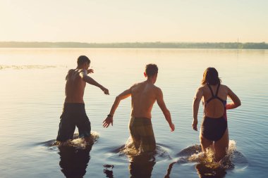 Neşeli arkadaşları koş su ve sahip eğlenceli - plaj tatil. Arkadan görünüm.