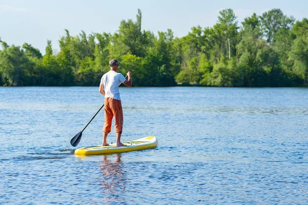 男は晴れた朝に大きな川で Sup ボードの上帆します スタンド アップ パドルボーディング 素晴らしいアクティブな野外レクリエーション 背面図 — ストック写真