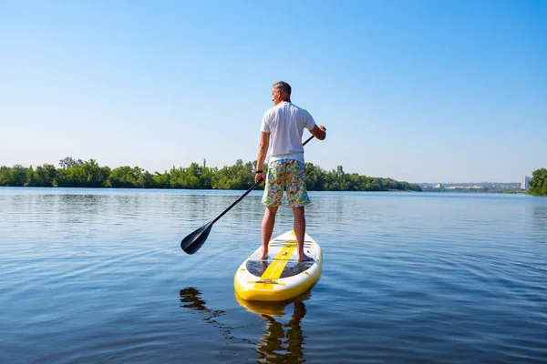 大人の男は 晴れた朝に大きな川で Sup ボードの上帆します スタンド アップ パドルボーディング 素晴らしいアクティブな野外レクリエーション 背面図 — ストック写真