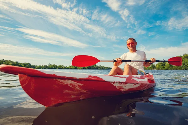 Happy adult man kayaking on the river at a sunny morning and enjoying life - water sport on the weekend. Wide angle.