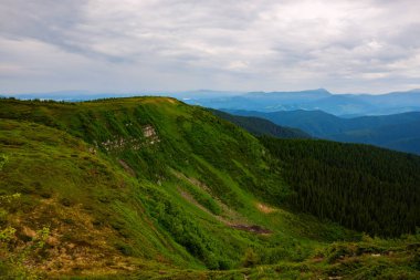 Muhteşem dağ manzarası - yeşil yemyeşil çim ve çalılar fırtına öncesi gri gökyüzü arka plan üzerinde kaplı bir dağ sirk yeşil dağ yamaçları oluştururlar. Geniş açı.
