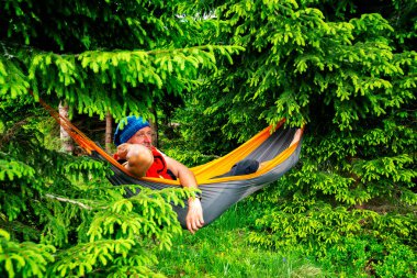 Çam ağaçları arasında yeşil dağ çayır üzerinde hamakta rahatlatıcı ve rüya maceraperest. Dağlarda epik seyahat.