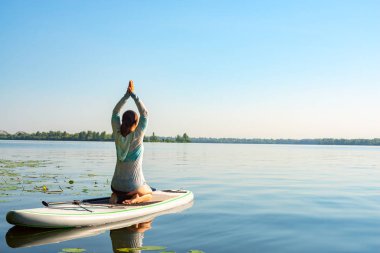 Pratik yoga bir Sup Kurulu sırasında güneşli sabah büyük bir nehir üzerinde erkek. Yukarı raket yatılı - stand doğada awesome Aktif istirahat. Arkadan görünüm.