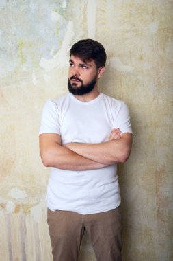 Şaşırmış sakallı genç adam pozlar Studio grunge duvar arka plan üzerinde