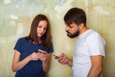 Rahat kıyafetler içinde odaklanmış genç çift evde onların akıllı telefonlar kullanır