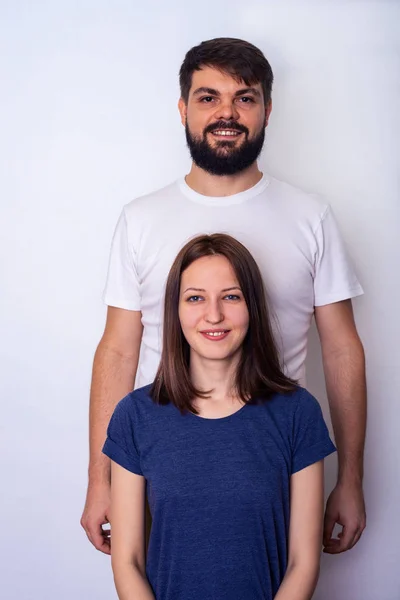 Young couple in casual clothes looks at camera in studio and smiles
