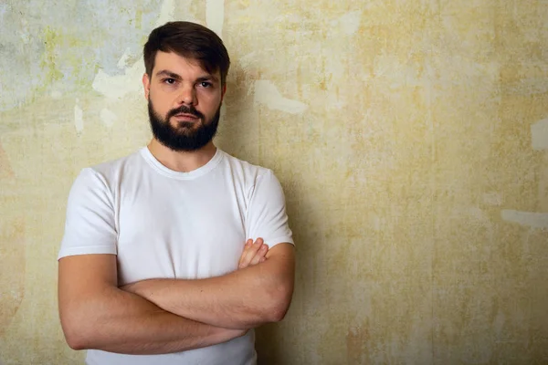 Sakallı genç adam pozlar Studio grunge duvar arka plan üzerinde