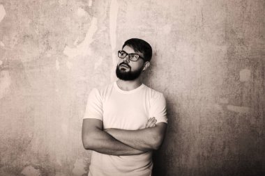 Sakallı genç adam Studio grunge duvar arka plan üzerinde gözlük teşkil etmektedir. Siyah ve beyaz vurdu 