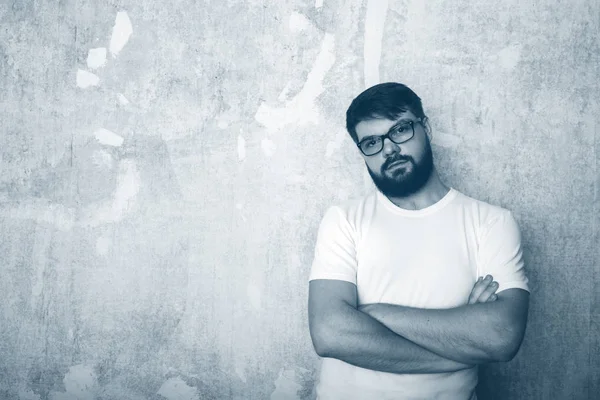 Sakallı genç adam Studio grunge duvar arka plan üzerinde gözlük teşkil etmektedir. Siyah ve beyaz vurdu 
