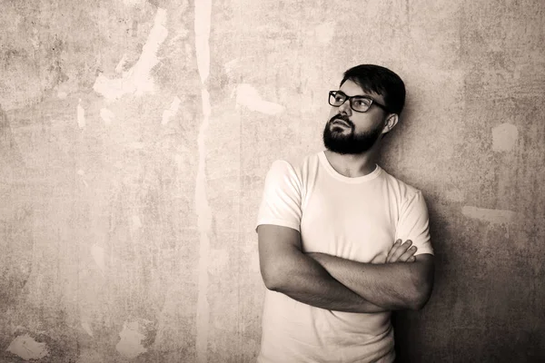 Sakallı genç adam Studio grunge duvar arka plan üzerinde gözlük teşkil etmektedir. Siyah ve beyaz vurdu 
