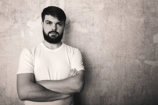 Sakallı genç adam Studio grunge duvar zemin teşkil etmektedir. Siyah ve beyaz stüdyoda vurdu