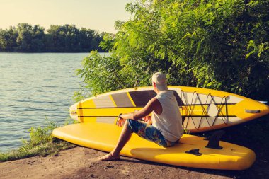 SUP sörfçü bir nehir gibi kanepe hayattan zevk ve bir şey hakkında düşünüyor sup kullanarak kamp içinde dinlendirici