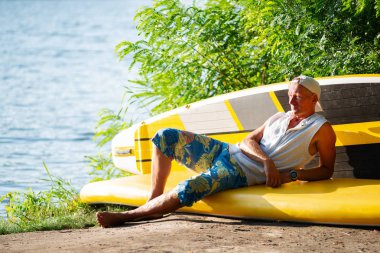 SUP sörfçü bir nehir gibi kanepe hayattan zevk ve bir şey hakkında düşünüyor sup kullanarak kamp içinde dinlendirici