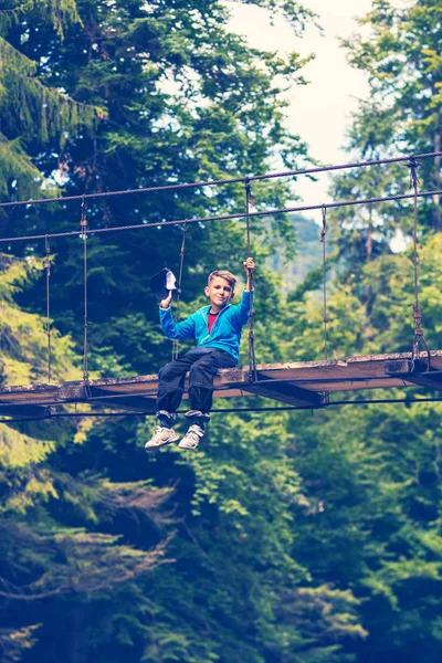 Küçük bir çocuk oturur bir asma köprü ve rüya. Bir vahşi aile ile harika bir macera. Vintage görüntü.