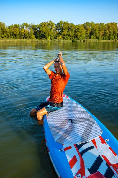 Funny guy, teenager relaxes on SUP board and having fun. Stand up paddle boarding - awesome active outdoor recreation.