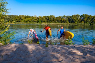 Neşeli arkadaşları ellerinde Sup komiteler ile sudan akşam ve having fun yaz aylarında çalıştırın. Yukarı raket yatılı - stand harika etkin açık rekreasyon. 