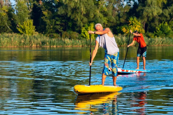 Happy friends paddling on a SUP board on large river and enjoying life. Stand up paddle boarding - awesome active outdoor recreation.