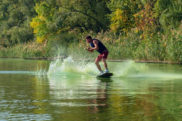 Wakeboarder odaklanmış yüz rides sıçramalarına, kablo Park güneşli gün eğitim sırasında arasında.