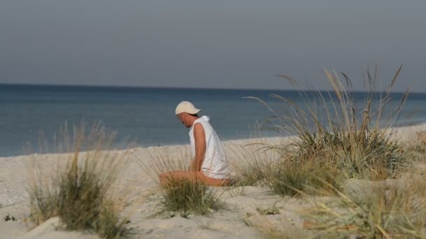 Człowiek Siedzi Plaży Medytacji Przez Rysunek Piasku Patrząc Dal — Wideo stockowe