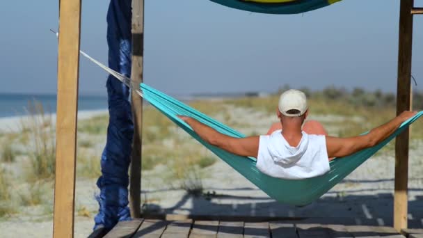 Mennesket Slapper Hengekøye Bungalow Veranda Beundrer Det Turkise Havet Foran – stockvideo