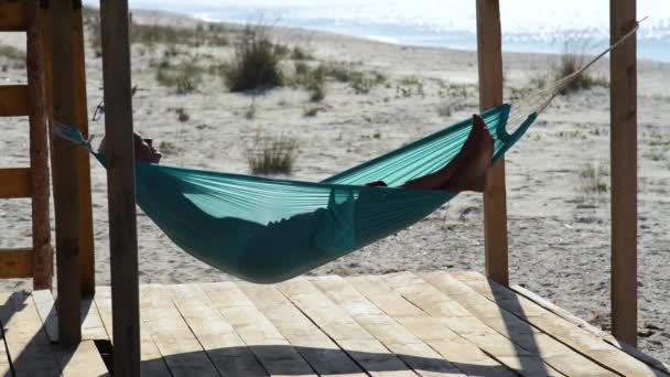 Man Relaxes Hammock Bungalow Veranda Admiring Turquoise Sea Front Him — Stock Video