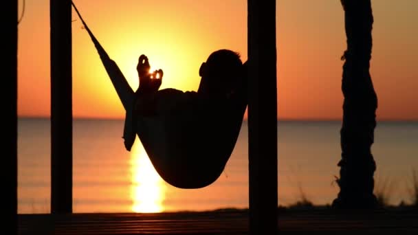 Człowiek Relaksuje Hamaku Werandzie Bungalow Podziwiając Zachód Słońca Nad Morzem — Wideo stockowe