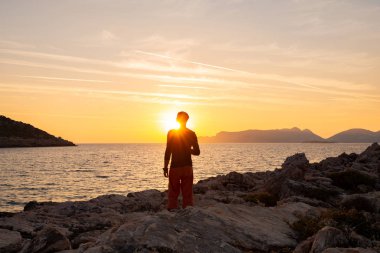 Erkek gezgin muhteşem altın günbatımı güzel bulutlar deniz ile görünüyor. Choban defne, Likya yolu, Mugla, Turkey