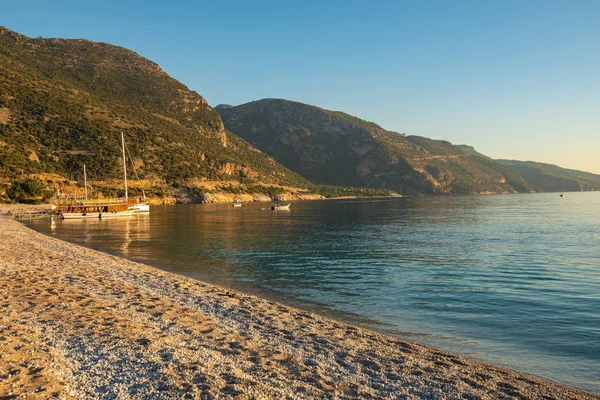 Sailboats in turquoise waters of the Mediterranean Sea surrounded by rocky shores during sunset - Oludeniz, a tourist landmark in Turkey.