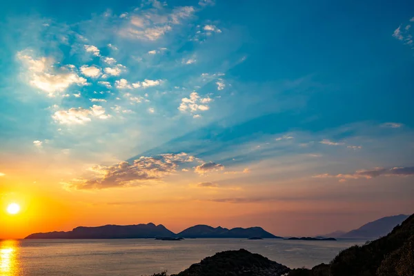 Kaş, Türkiye - Likya yol boyunca seyahat yakınındaki muhteşem gün batımı Akdeniz üzerinden. Turuncu Güneş ufukta Adaları mor denizde batar. Geniş açı.