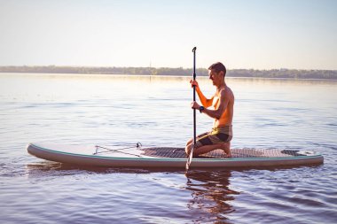 Büyük Nehri üzerinde bir Sup tahta kürek çekmeye yorgun bir adam. Yukarı raket yatılı - stand harika etkin açık eğitim.