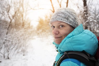 Kar arasında ormandaki izinde gülümseyen kadın portresi ağaçlar, sessiz kış gününde kaplı..
