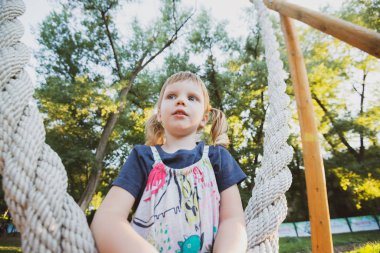 Küçük kız Şehir Parkı içinde bir salıncak üzerinde eğleniyor. Vintage tarzı görüntüde. Geniş açı