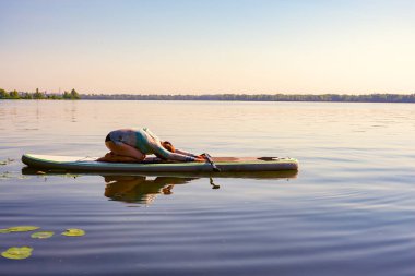 Kadın pratik yoga bir Sup kurulu büyük bir Nehri üzerinde. Yukarı raket yatılı - stand doğada awesome etkin eğitim.