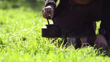 Gezgin bir gaz yakıcı bir gür yeşil çim - güneşli sabahı Doğa kampı arasında iki çelik kupalar yanındaki küçük bir çelik su ısıtıcısı koyar.
