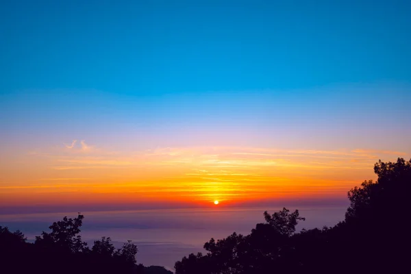 Orange sun sets on the horizon over the purple sea - amazing scene during sunset along the Lycian way, Turkey.