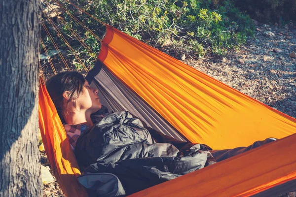 Traveler woman sleeping in a hammock on a rocky seashore of mediterranean sea - adventure travel along Lycian way, Turkey. Vintage image.