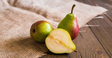 Kırmızı yanaklı armut ve çul ahşap tahta üzerinde 