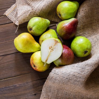 Kırmızı yanaklı armut ve çul ahşap tahta üzerinde 