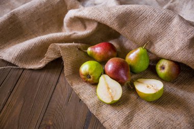Kırmızı yanaklı armut ve çul ahşap tahta üzerinde 