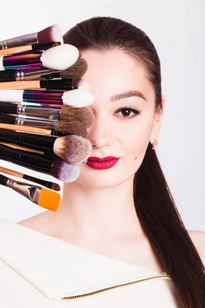 O rosto de uma linda garota e pincel de maquiagem no backgrou branco — Fotografia de Stock