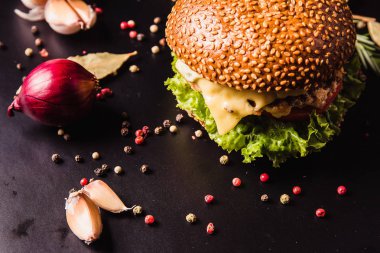 Siyah arka planda baharatlı lezzetli bir burger.