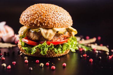 Siyah arka planda baharatlı lezzetli bir burger.