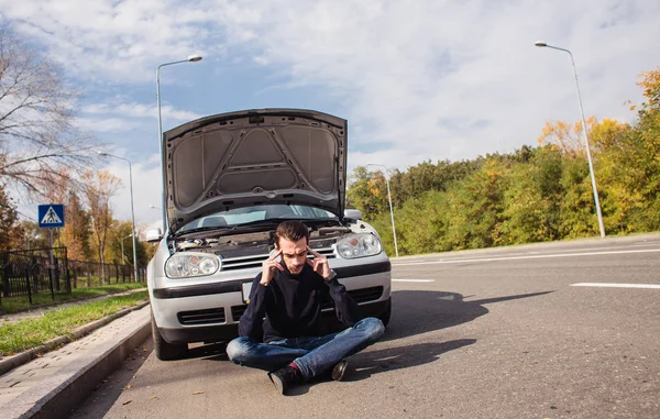 Arabasının arızası yüzünden umutsuzluğa düşmüş bir adam. 
