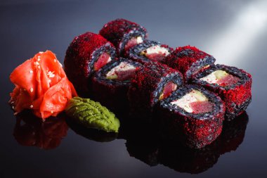 Suşi avokado ve ton balığı ile siyah bir arka plan üzerine alır. Geleneksel Japon mutfağı