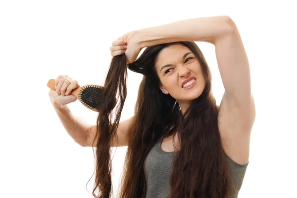 Uma jovem mulher não pode pentear o cabelo emaranhado problemático. Fundo branco fechar — Fotografia de Stock