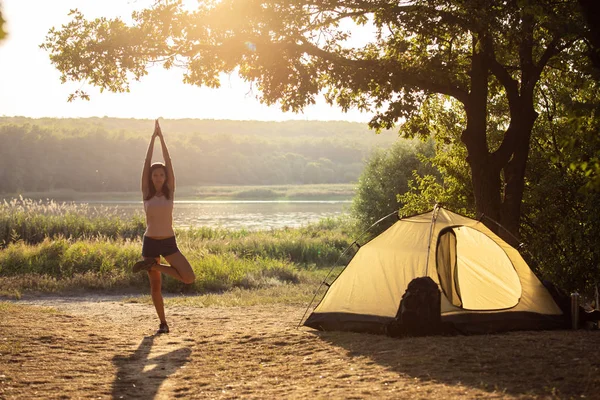 Jonge yogi vrouw doen oefeningen tegen de achtergrond van de r — Stockfoto