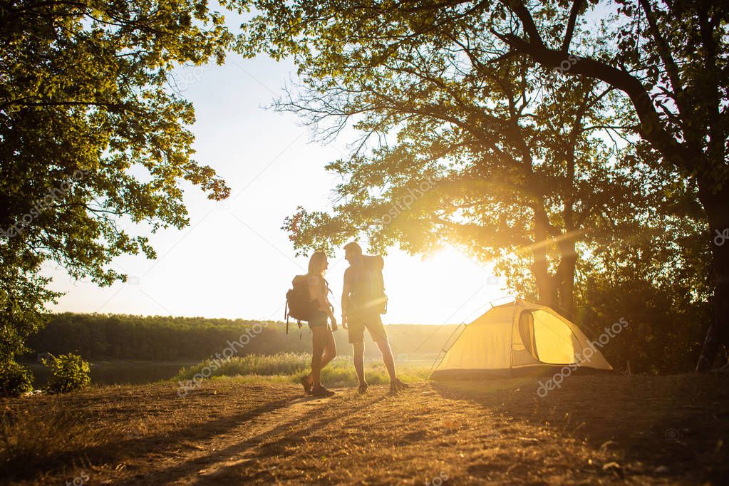 A man and a woman in a hiking trip with backpacks near a tent at