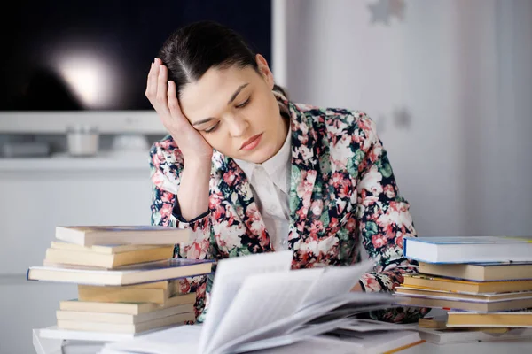 Een jonge vrouw zit voor een stapel papieren — Stockfoto