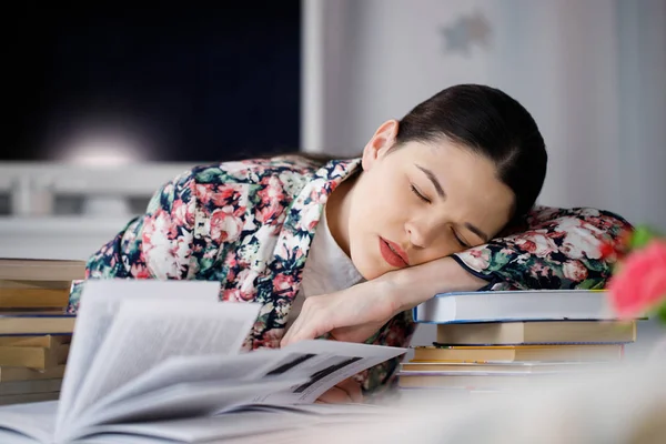 A young woman asleep  in front of a pile of papers