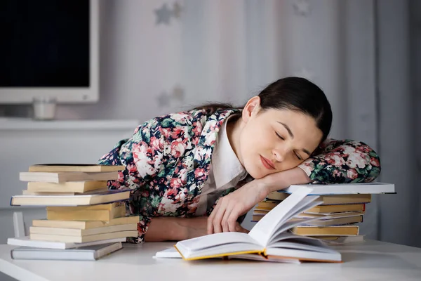 Een jonge vrouw in slaap voor een stapel papieren en een compute — Stockfoto